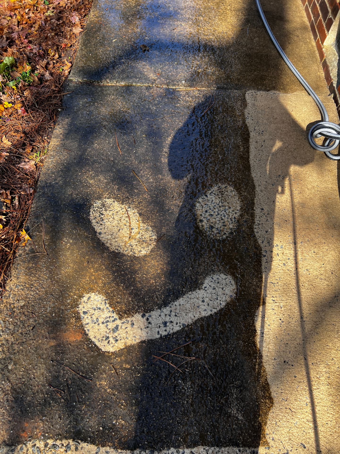 Smiley face cleaned into the grime on a sidewalk